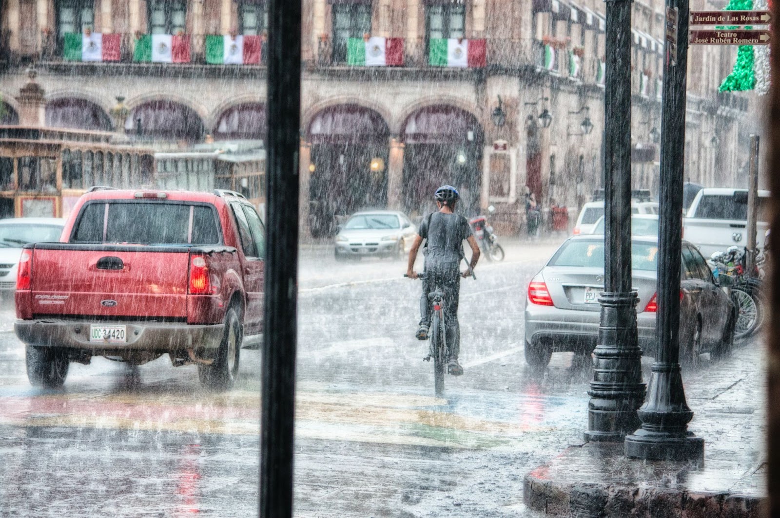 大雨の中を進む車とずぶ濡れの自転車を運転している人