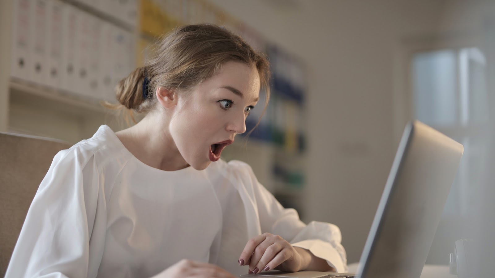 Research paper 4: a woman in shock is looking at her laptop 