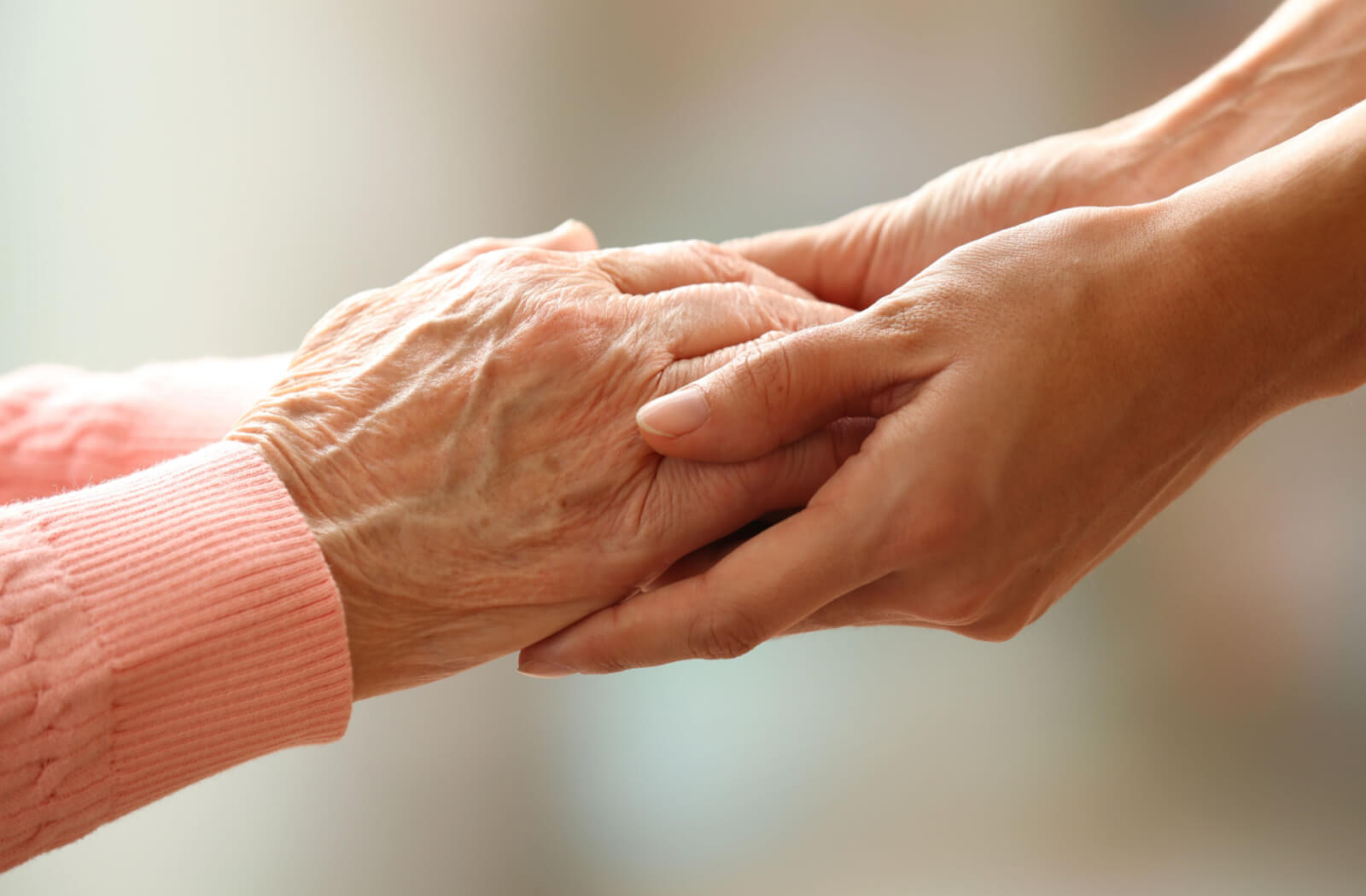 a younger person holds the hands of a senior with short-term memory loss to support communication