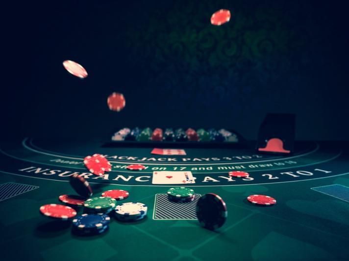 Meja kasino blackjack dengan kartu dan chip terbang di udara.