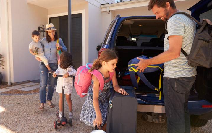An excited family of five are loading up their SUV to travel to a new short-term rental adventure.