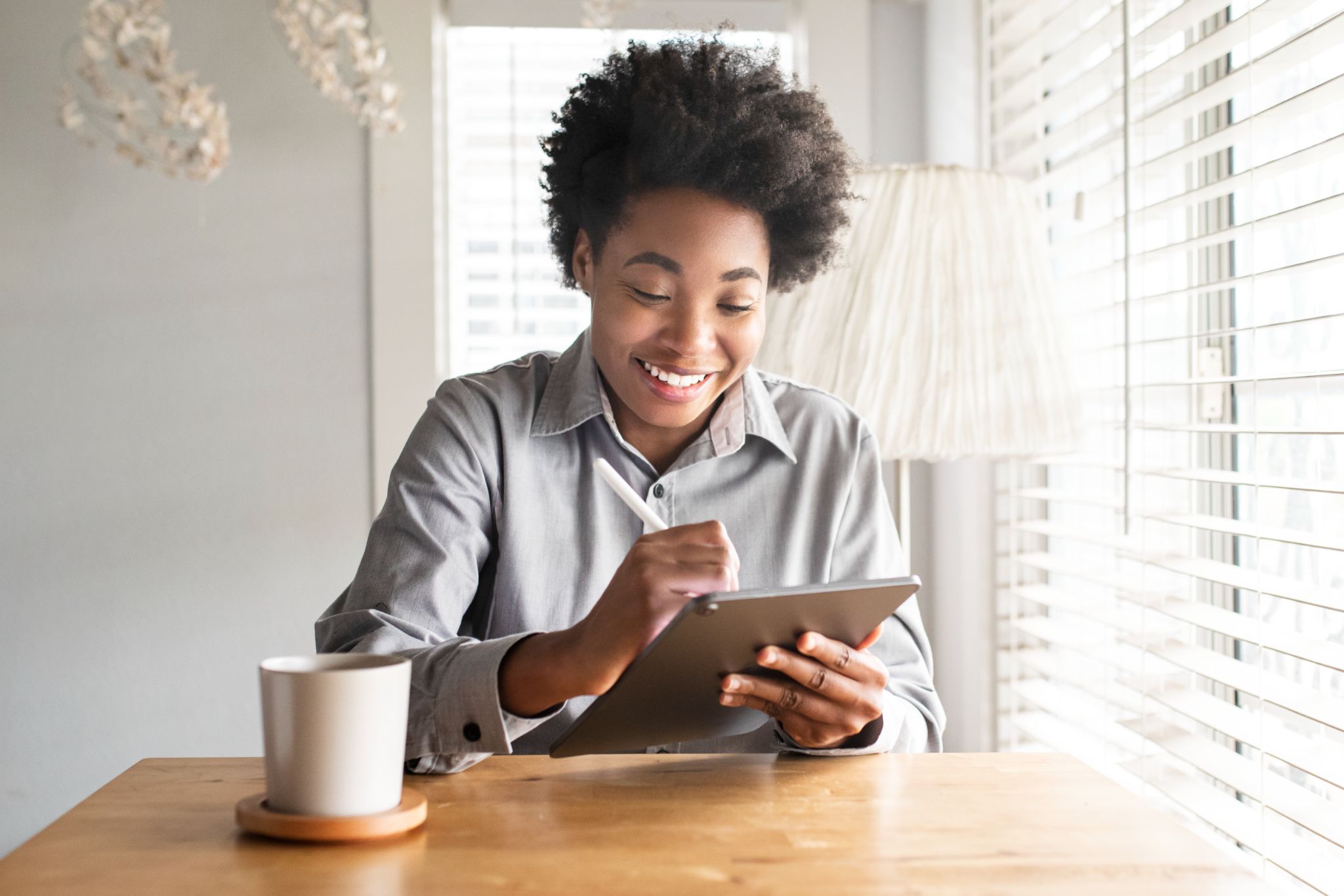 mulher negra trabalhando sorridente no tablet.
