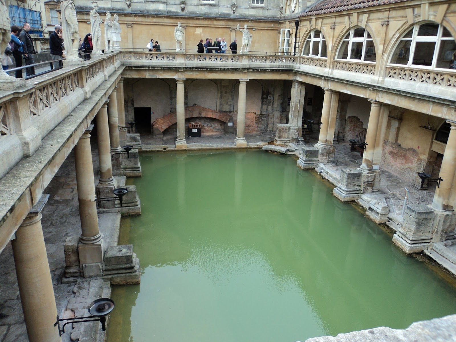 traditional roman baths in bath, united kingdom. the bath is observed by tourists from the balcony one level above. tourist attraction in united kingdom, must-see on a UK road trip