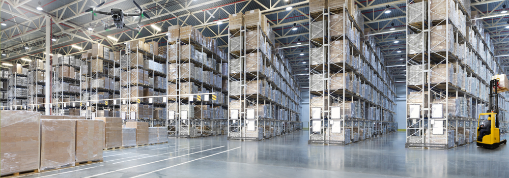 interior of very large warehouse with a dozen racks, a forklilft, and some wrapped pallets of cartoned goods.