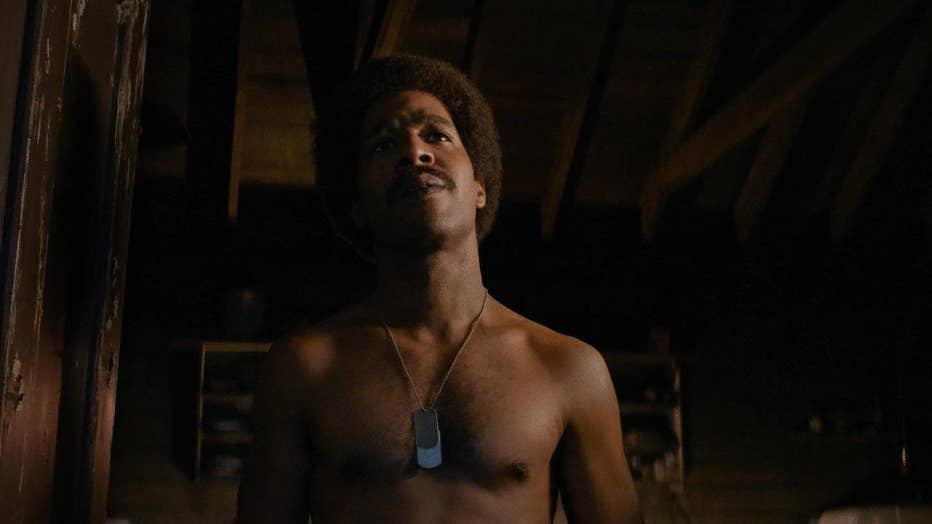 Kid Cudi's character, Jackson Hole, stands shirtless in a room, with his dogtags hanging on a necklace.
