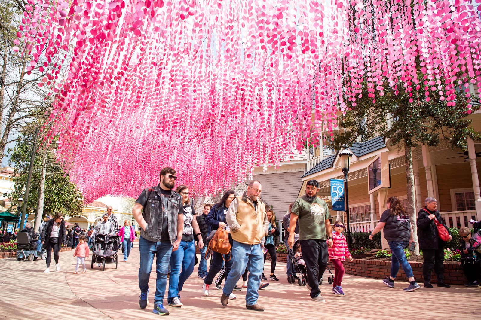 Guests walk under glittering pink sequins in the Showstreet Area of Dollywood on the park's opening day for pass holders on Friday, March 10, 2023. Dollywood is currently celebrating the 50th anniversary of "I Will Always Love You," one of Parton's biggest hits.