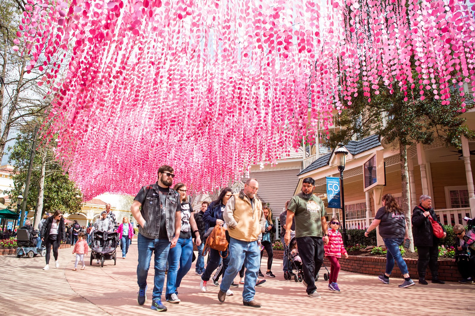 Guests walk under glittering pink sequins in the Showstreet Area of Dollywood on the park's opening day for pass holders on Friday, March 10, 2023. Dollywood is currently celebrating the 50th anniversary of "I Will Always Love You," one of Parton's biggest hits.