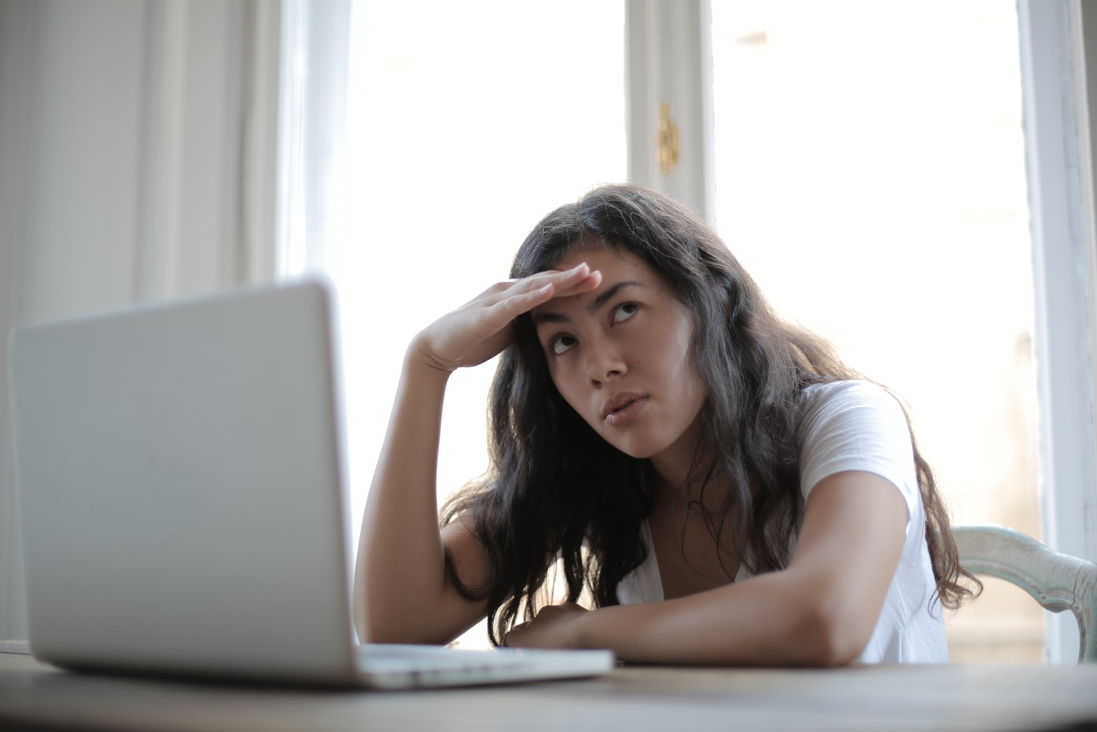 A woman staring at a laptop looking confused as she considers using a loan broker