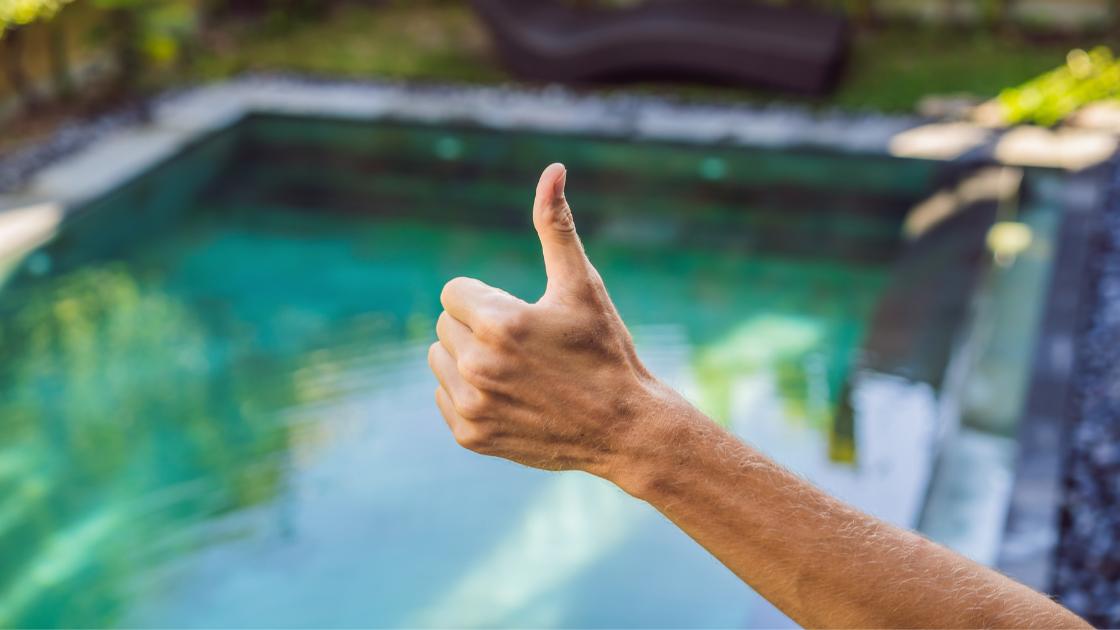 A thumbs up in front of a pool.