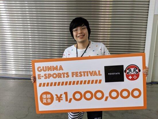 第1回障害者eスポーツ大会2019 GUNMAでLeague of Legends」をプレイし優勝したGreen Birdさんが、優勝賞金100万円のパネルを持っている写真。