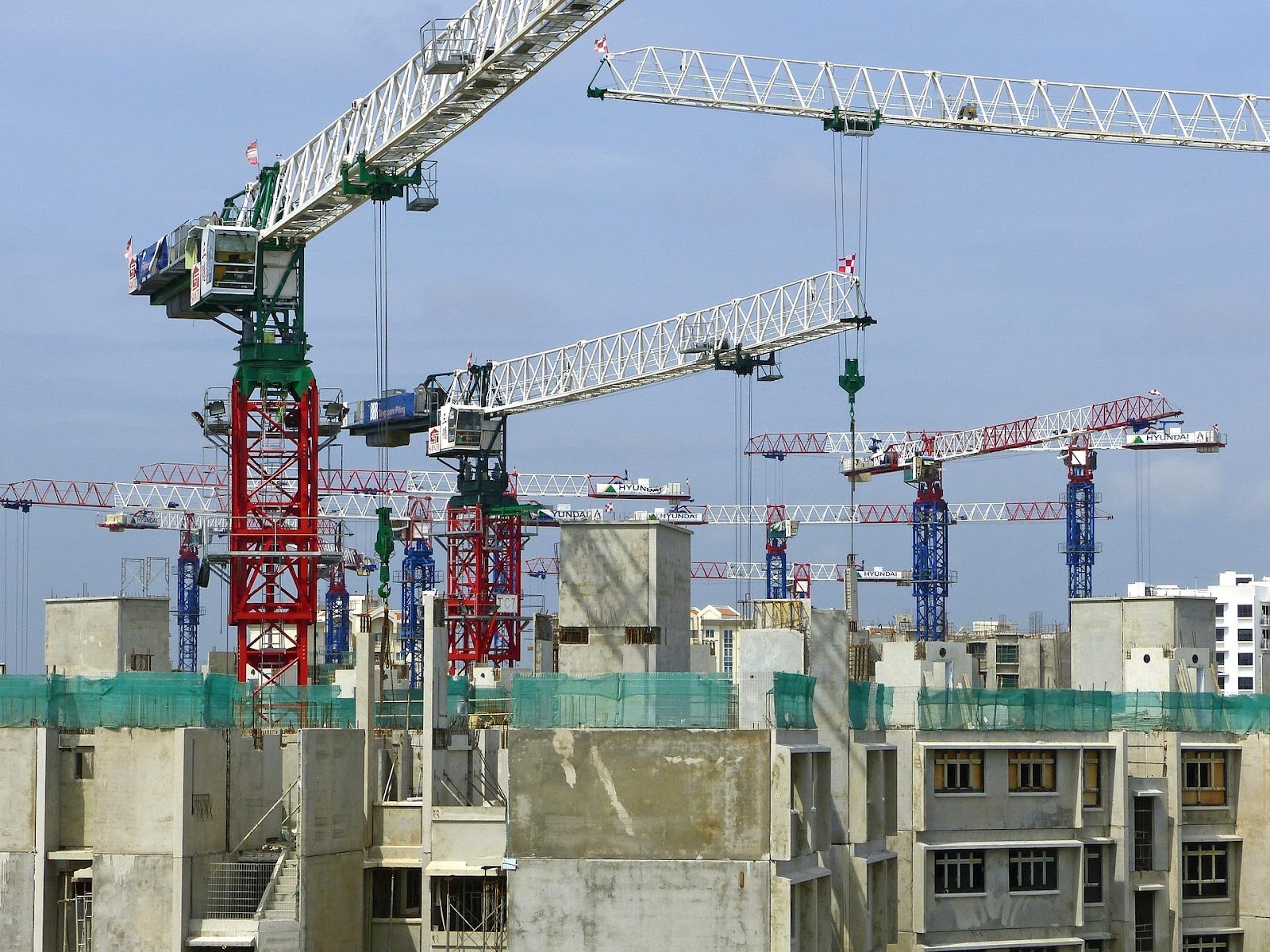 A construction site with multiple cranes over concrete buildings.