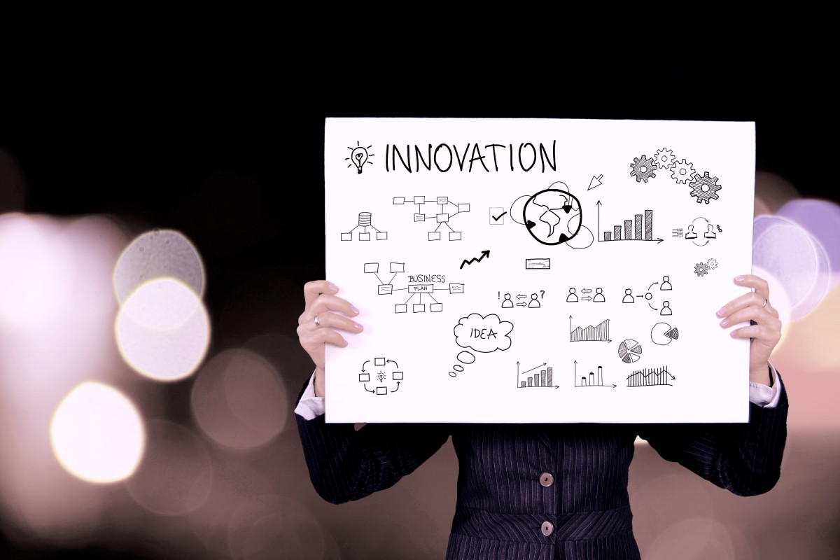 Programas de inovação: homem de negócio segurando banner com a palavra "innovation" e símbolos de inovação.