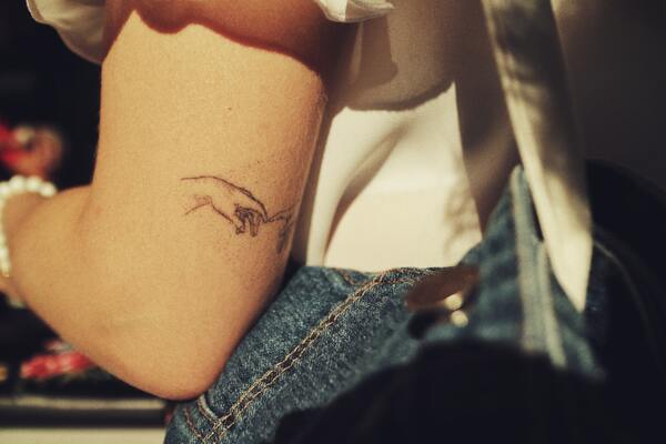 Foto do braço de uma mulher com uma tatuagem na parte de trás do braço 