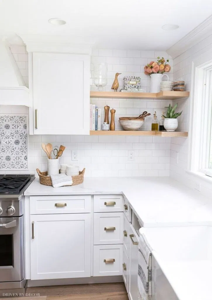 kitchen with white shaker cabinets and cool brass cabinet hardware. bright white countertops and white subway tile backsplash are accentuated by a window casting natural light