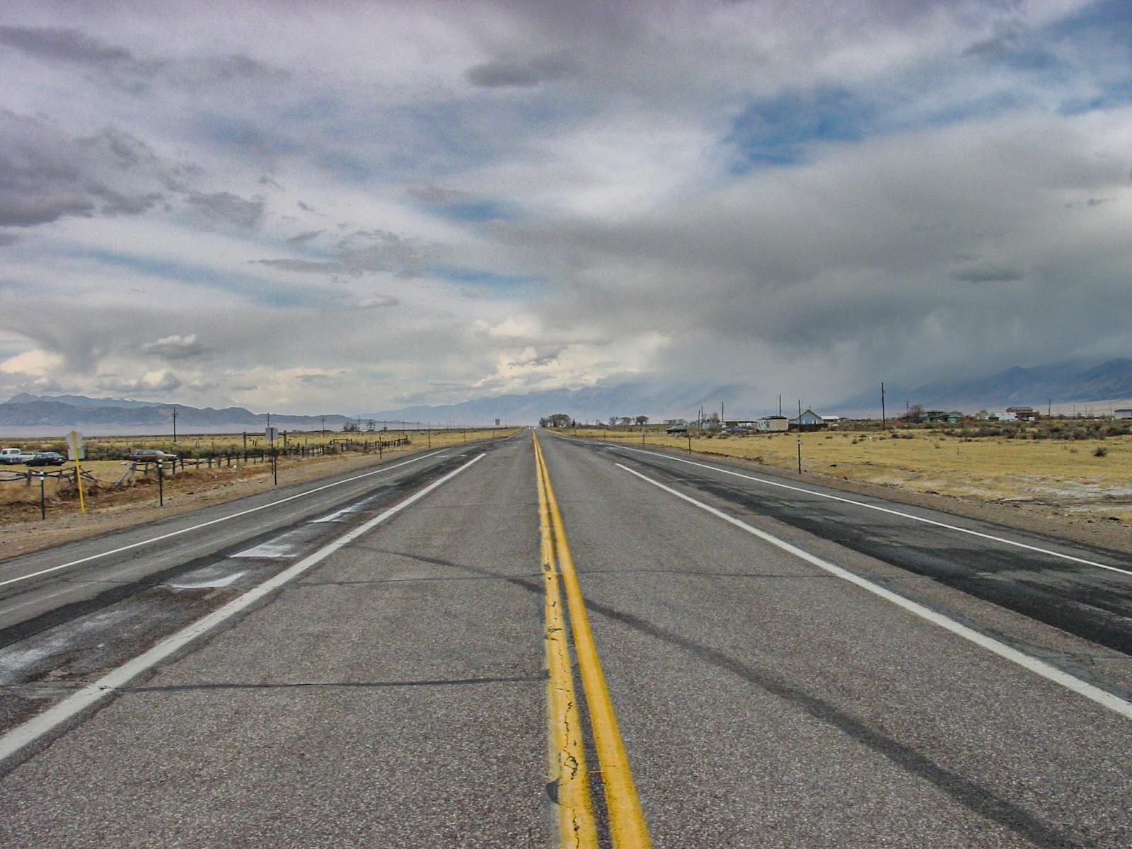 The centerline of a highway stretches into the distant dark clouds.