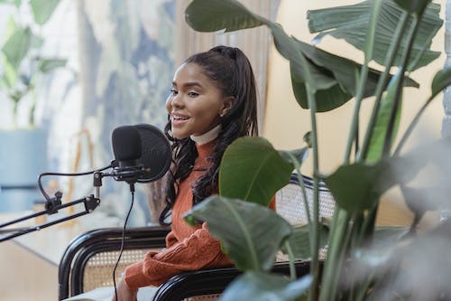 Free Happy young black woman singing during radio program Stock Photo