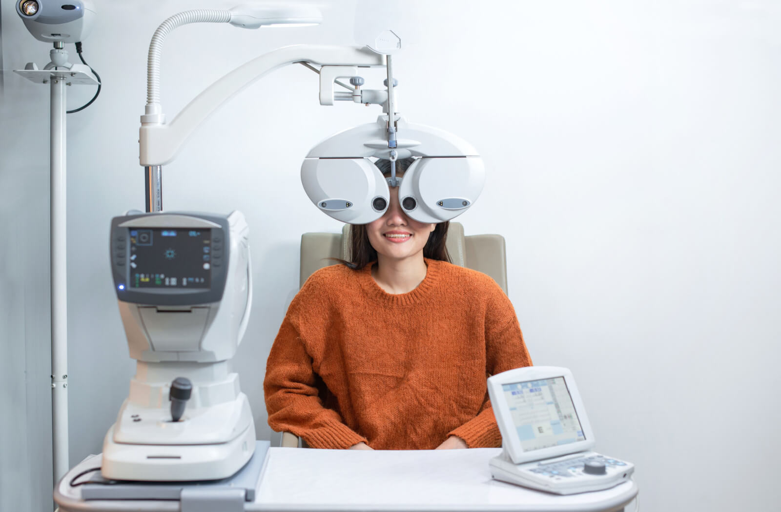 A woman sitting in an optometrist's office looking into a machine that tests her vision.