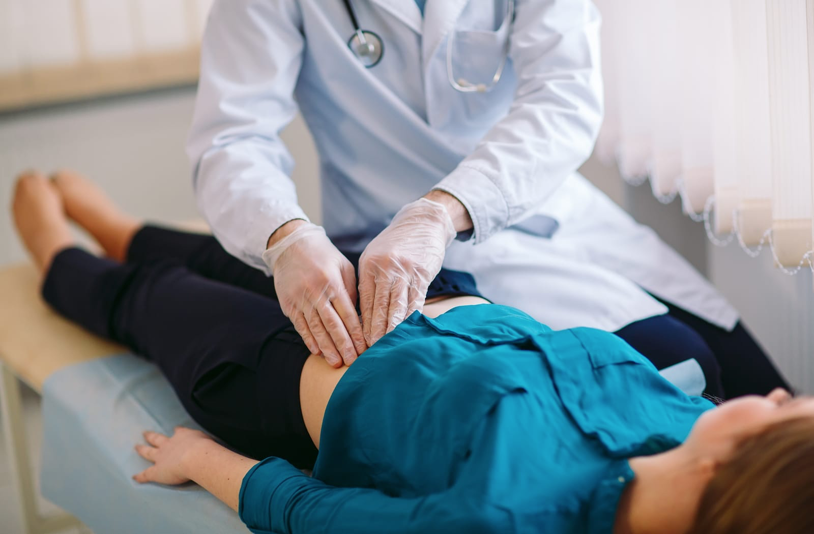 Doctor examines woman's abdomen
