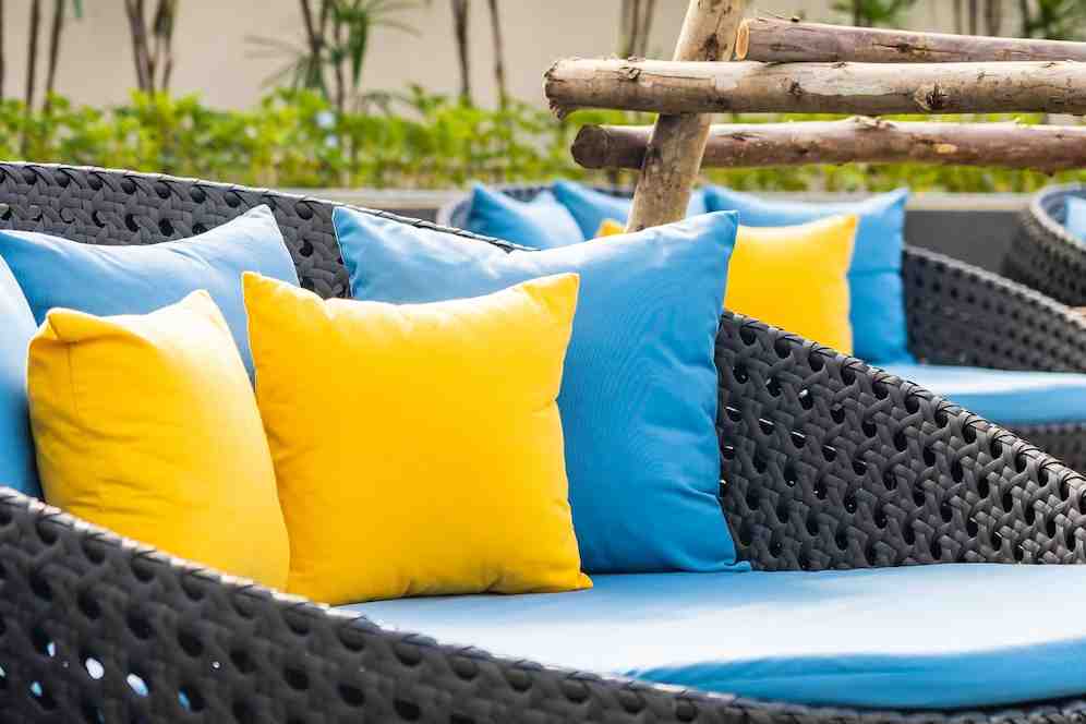 A patio with weaved chairs and colored pillow covers.