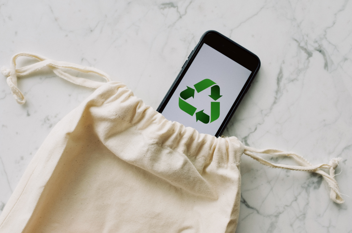 sacola de pano com um celular mostrando o símbolo da sustentabilidade