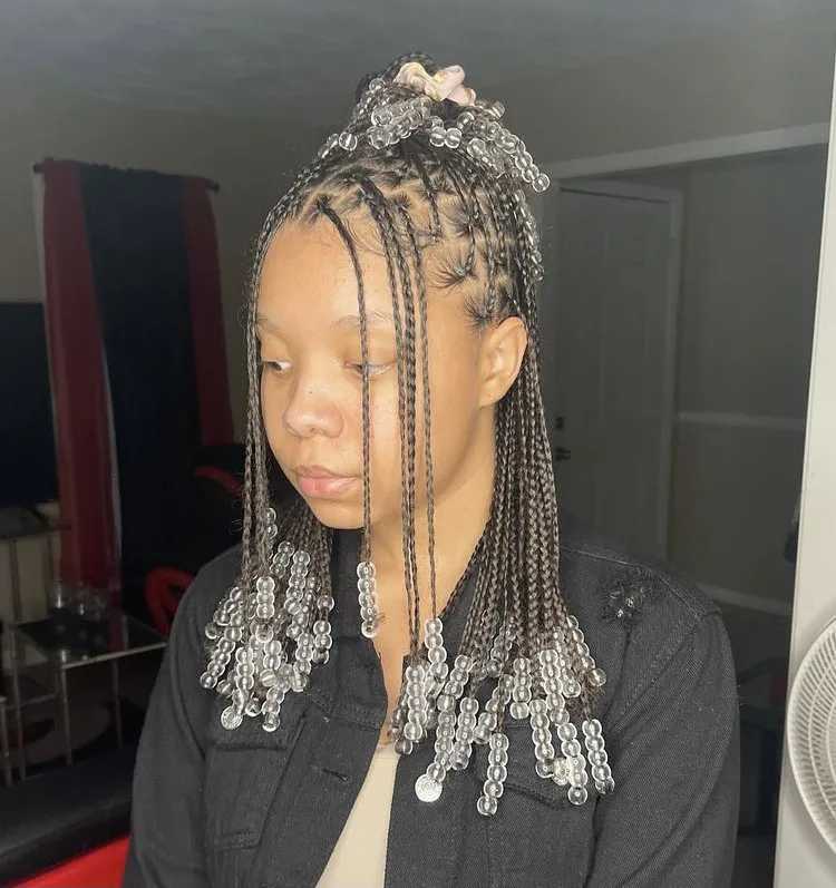 Full view of a lady showing off her small box braids with beads
