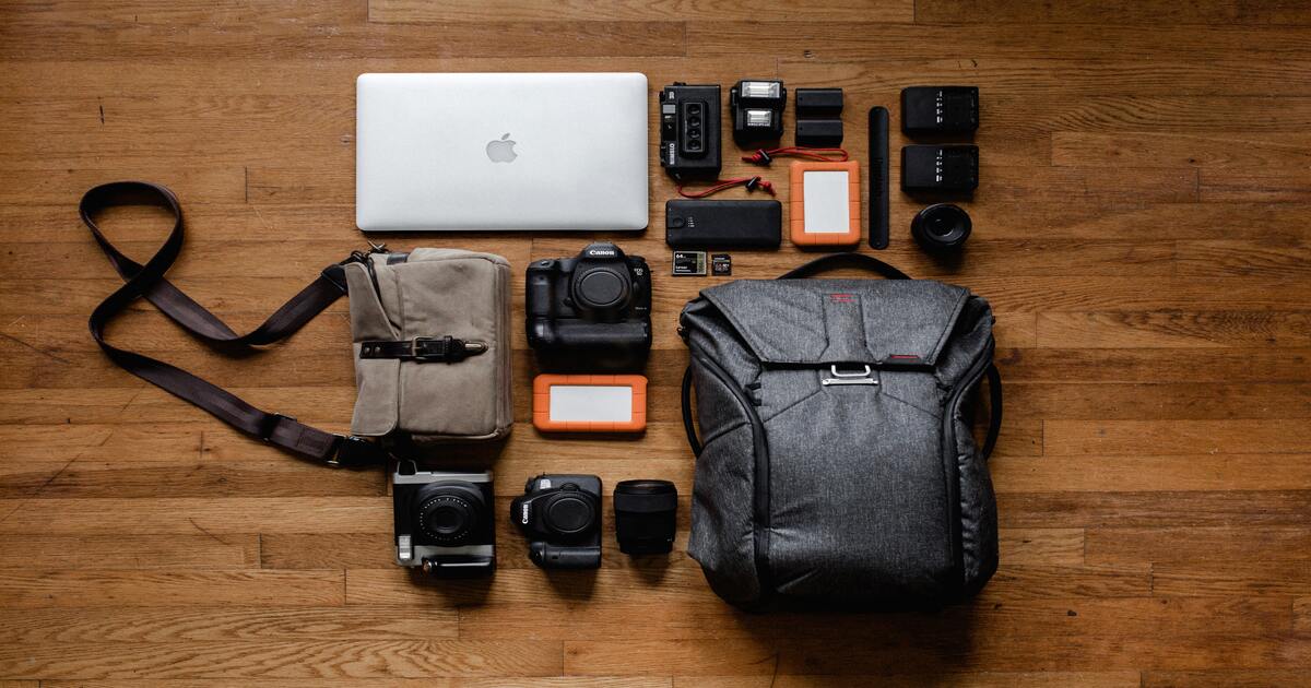 Small business holiday gift guide–A bird’s eye view image of various tech products like cameras and laptops on a wooden floor. 