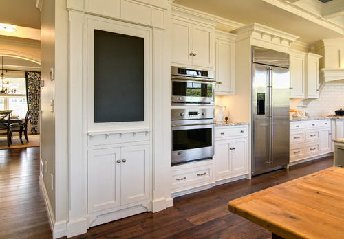 white hidden pantry door with white shaker cabinets and chalkboard