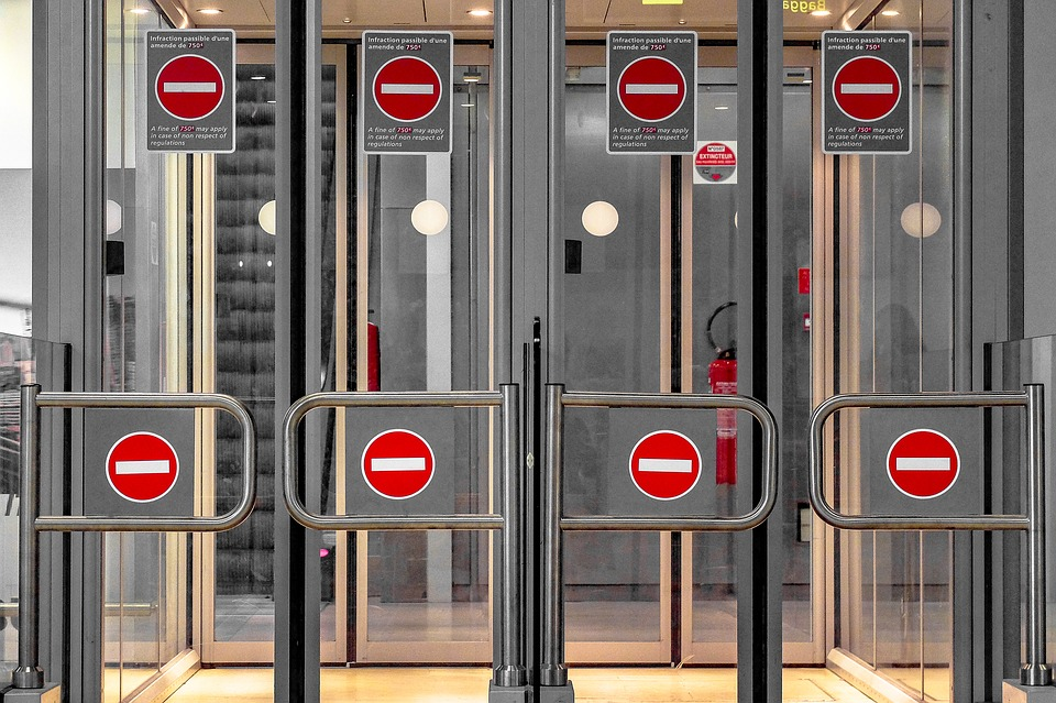 a few rows of silver airport security gates with red stop signs