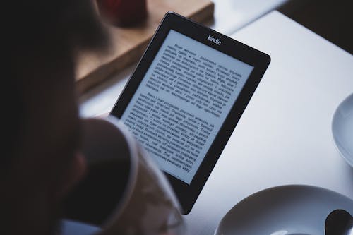 Free Person Using E-book Reader While Drinking Coffee Stock Photo