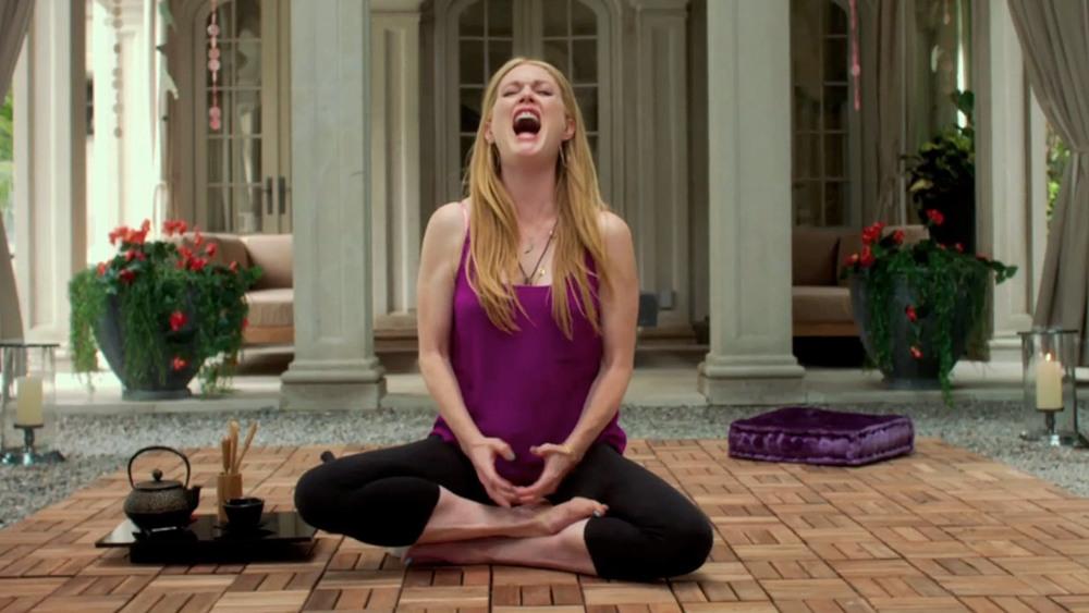 Julianne Moore as Havana in 'Maps to the Stars' (2014). Havana, wearing leggings and a purple tank top, is sitting cross legged on a patio, with a Japanese tea set and cushion beside her. She is in a cross-legged yoga pose, but her face is contorted in a scream.