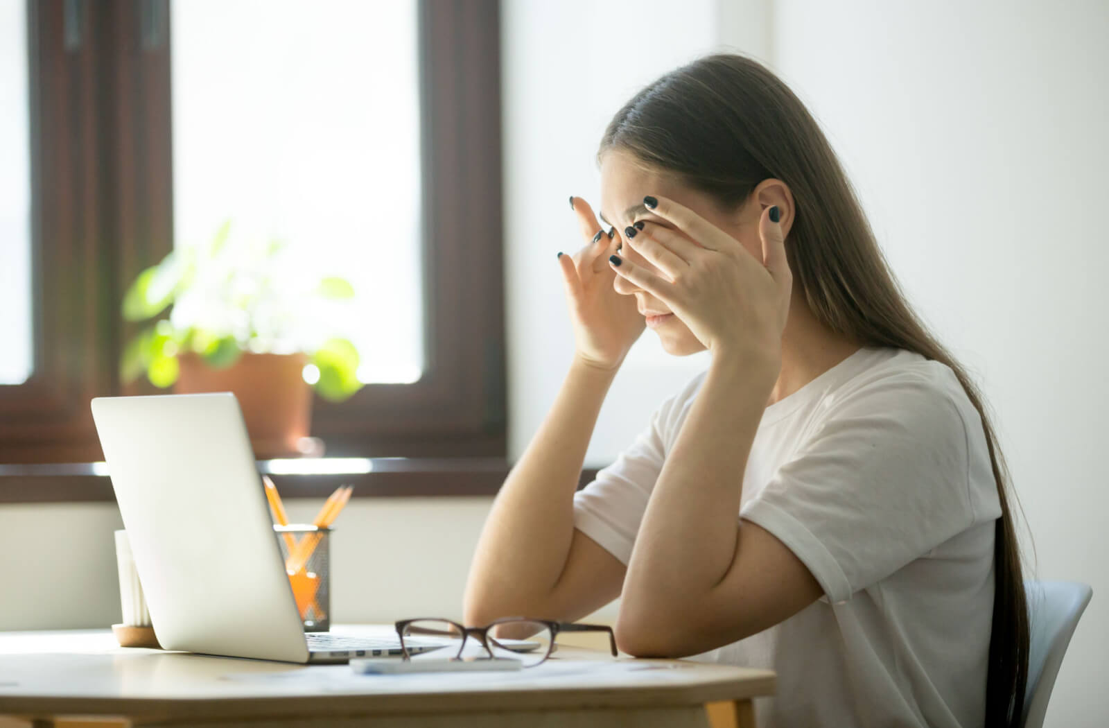 a woman holds her temples in attempt to relieve her headache from eye strain