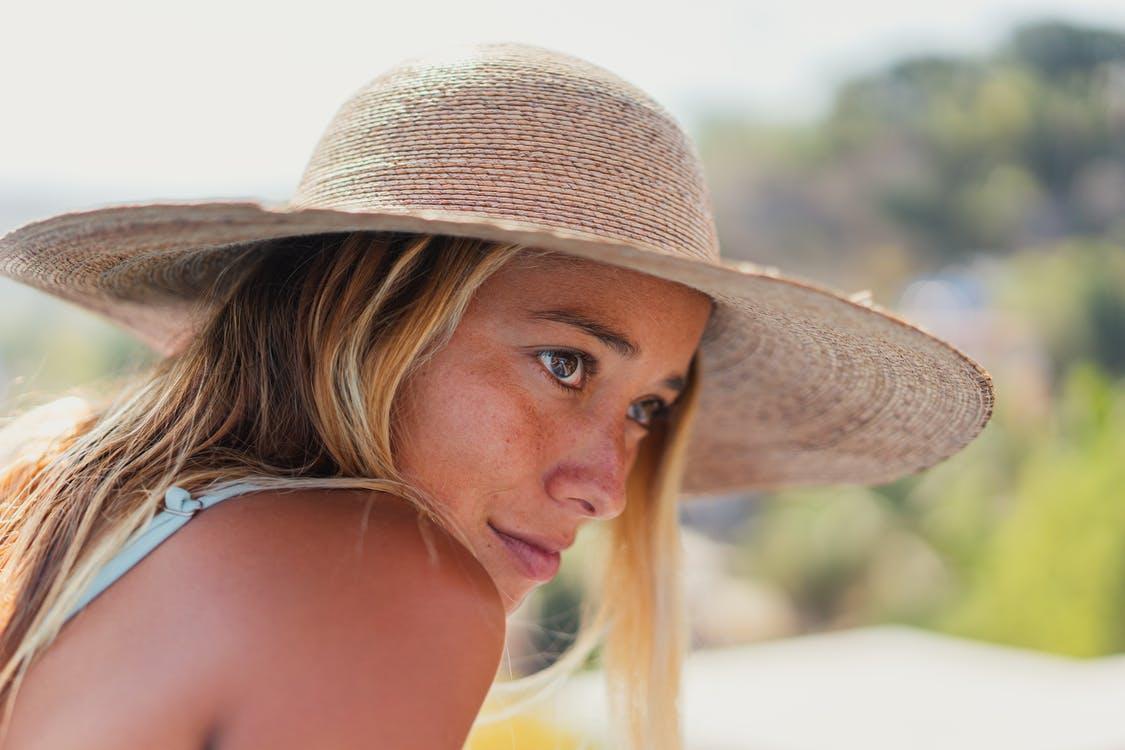 A blonde woman wearing a wide-brimmed straw sun hat.