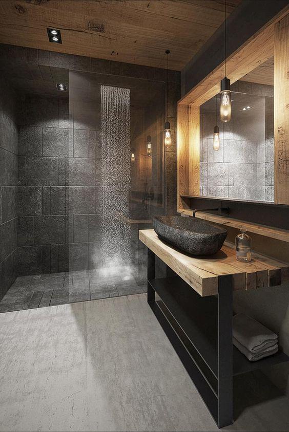 Banheiro com revestimentos cinza por todo banheiro, madeira utilizada para revestir o teto, a bancada e o suporte do espelho