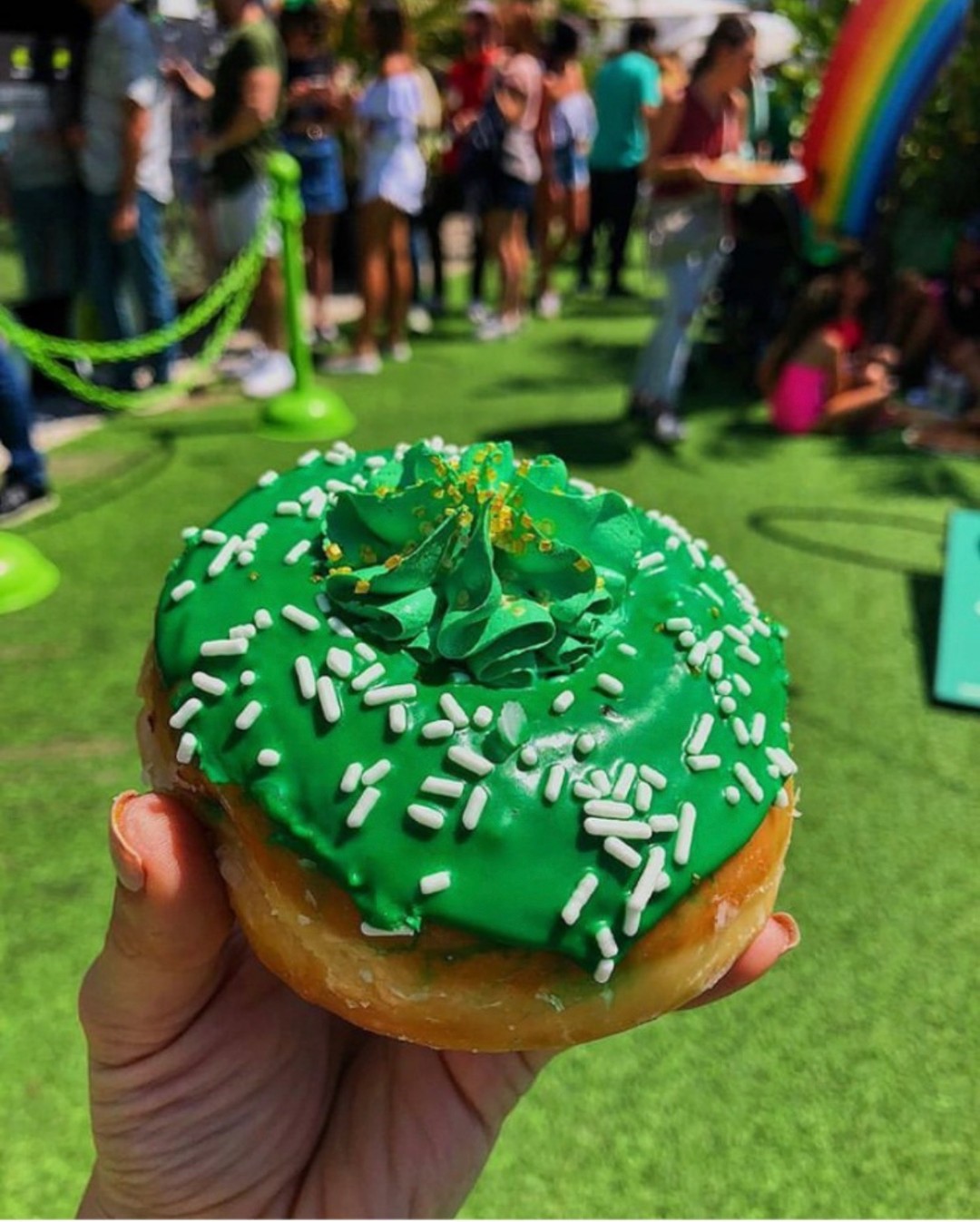 glazed donut with green icing and sprinkles, festival in the background