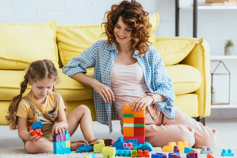 Mom teaching cooperative play to daughter using blocks