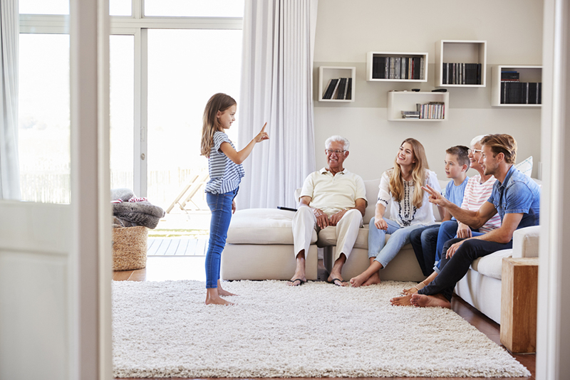 Young girl playing charades with family to learn verbs for kids