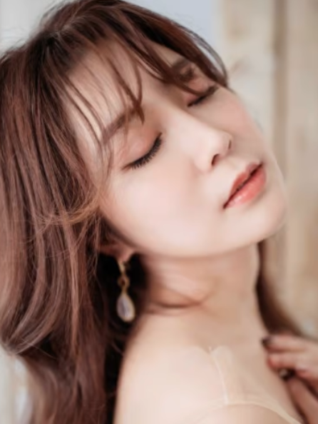 Photo of a woman with brown hair and brown bangs, peach lips
