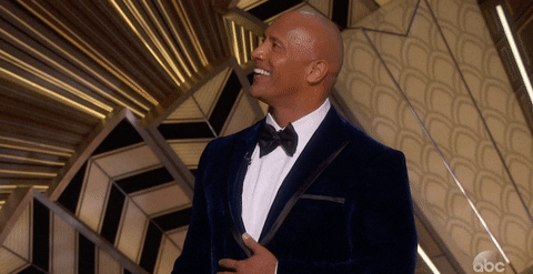 Dwayne The Rock Johnson looking at the audience at an awards show, smiling and nodding.