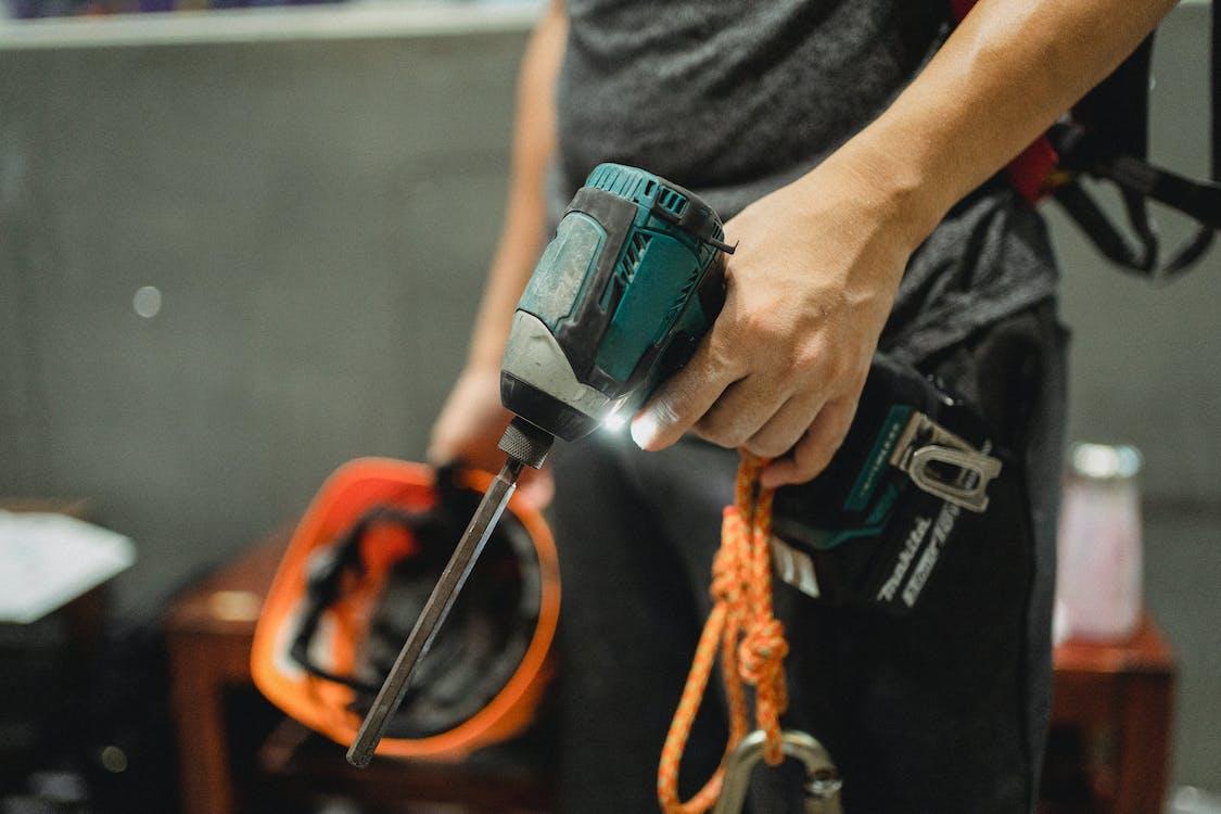 Free Crop repairman standing with working screwdriver and orange helmet Stock Photo