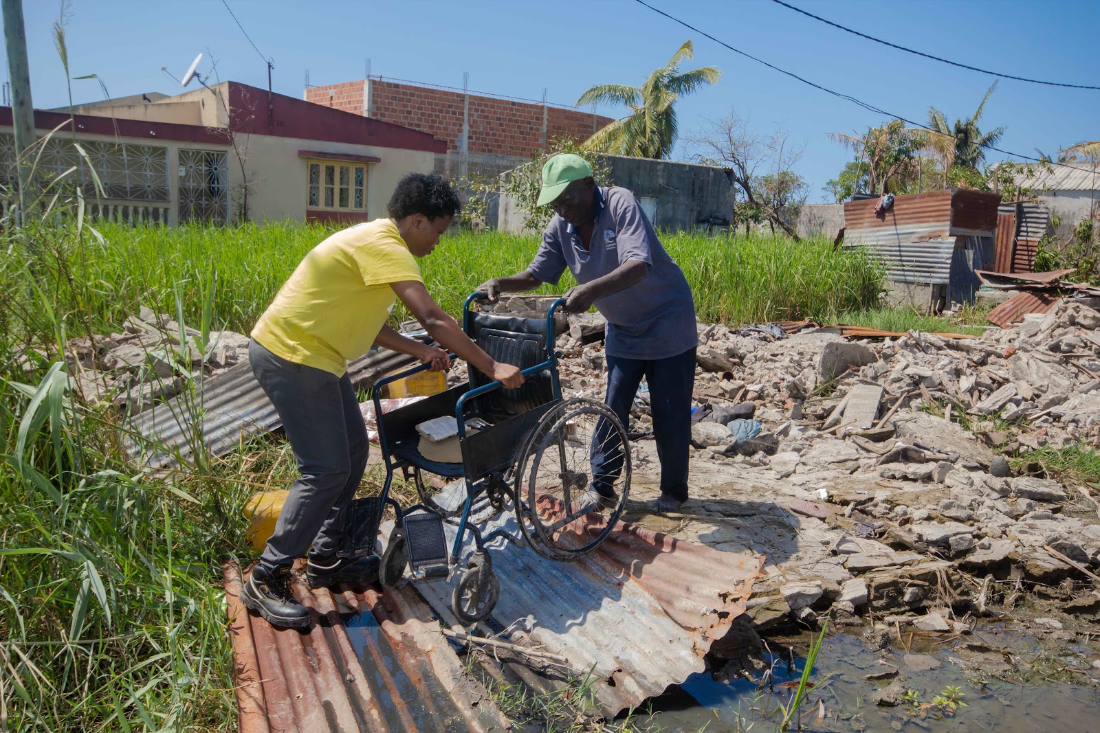 Zwei Menschen räumen nach einer Flutkatastrophe auf. Sie tragen einen Rollstuhl - ein Zeichen darauf, dass Menschen mit Behinderungen stärker von der Erderhitzung betroffen sind.
