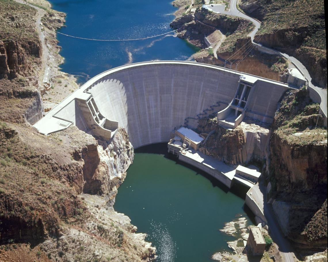 Arial image of the Roosevelt dam with desert landscape on both sides and dam in the middle with water on the top and bottom.