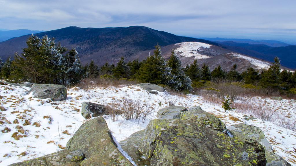 A wintery summit overlooking a mountain landscape.
