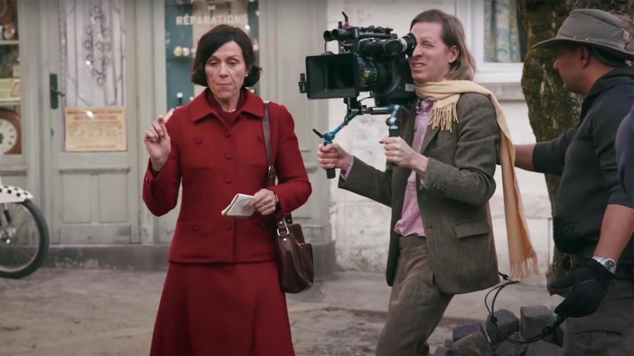 Frances Mcdormand as Lucinda Krementz being filmed by Wes Anderson in a behind the scenes photo.