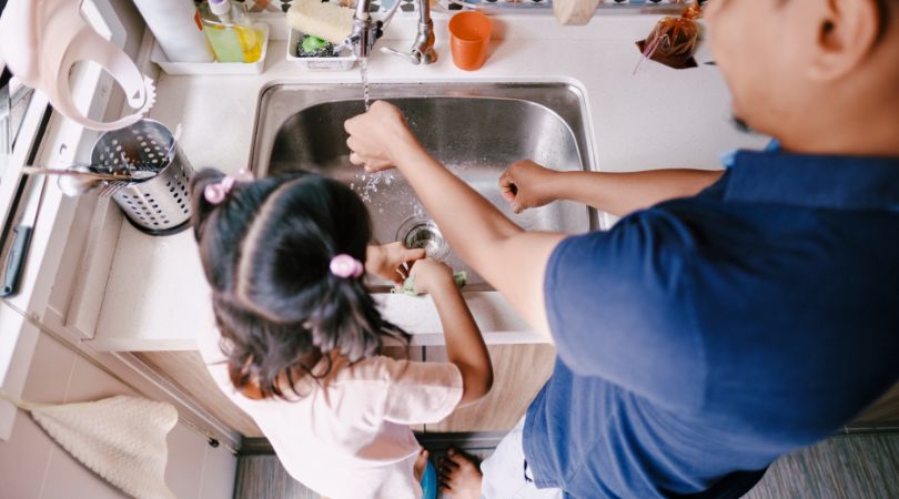 an adult and a child washing out the sink