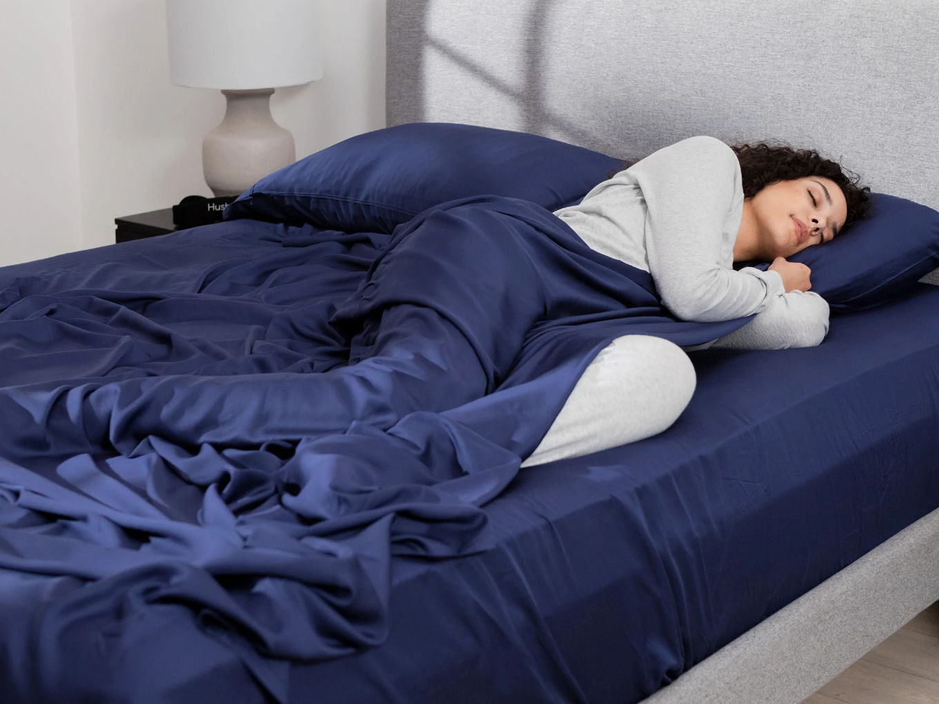 Woman sleeping soundly under dark blue sheets