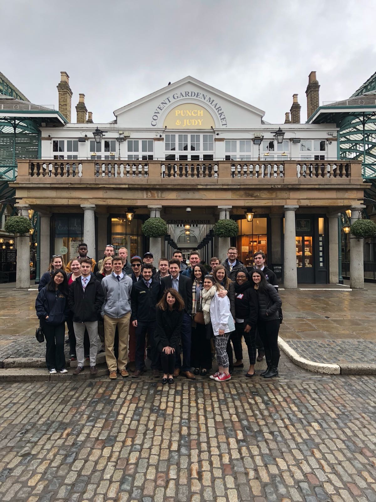 A group standing on a cobble stone street in front of a building that reads Covent Garden