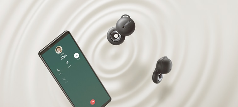 Два наушника LinkBuds серого цвета рядом с телефоном Sony Xperia на вихрящемся кремовом фоне