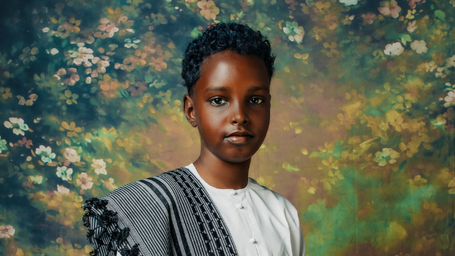 posed portrait of a young black person against a floral backdrop