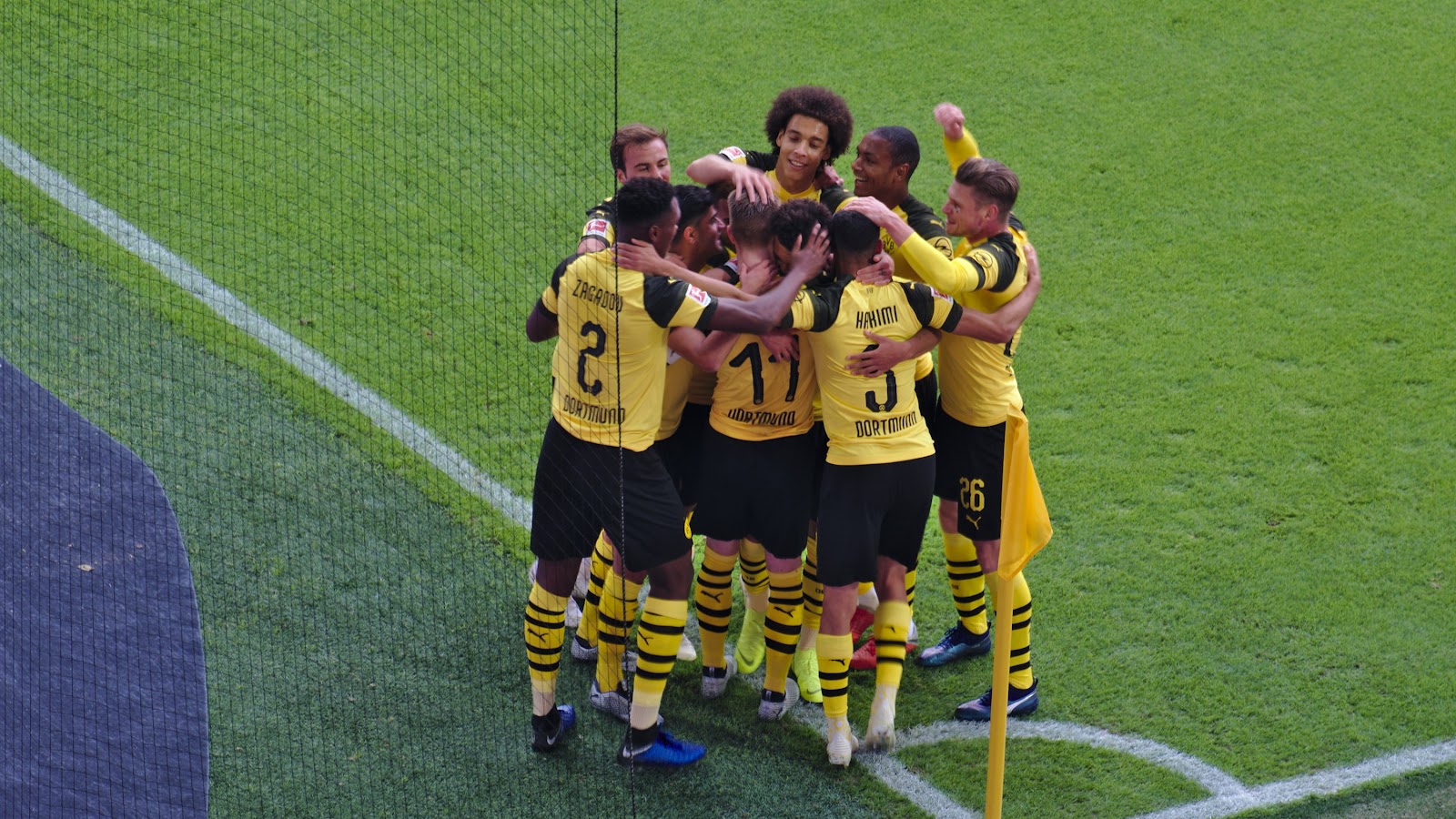 Borussia Dortmund players gather by a corner flag to celebrate a goal