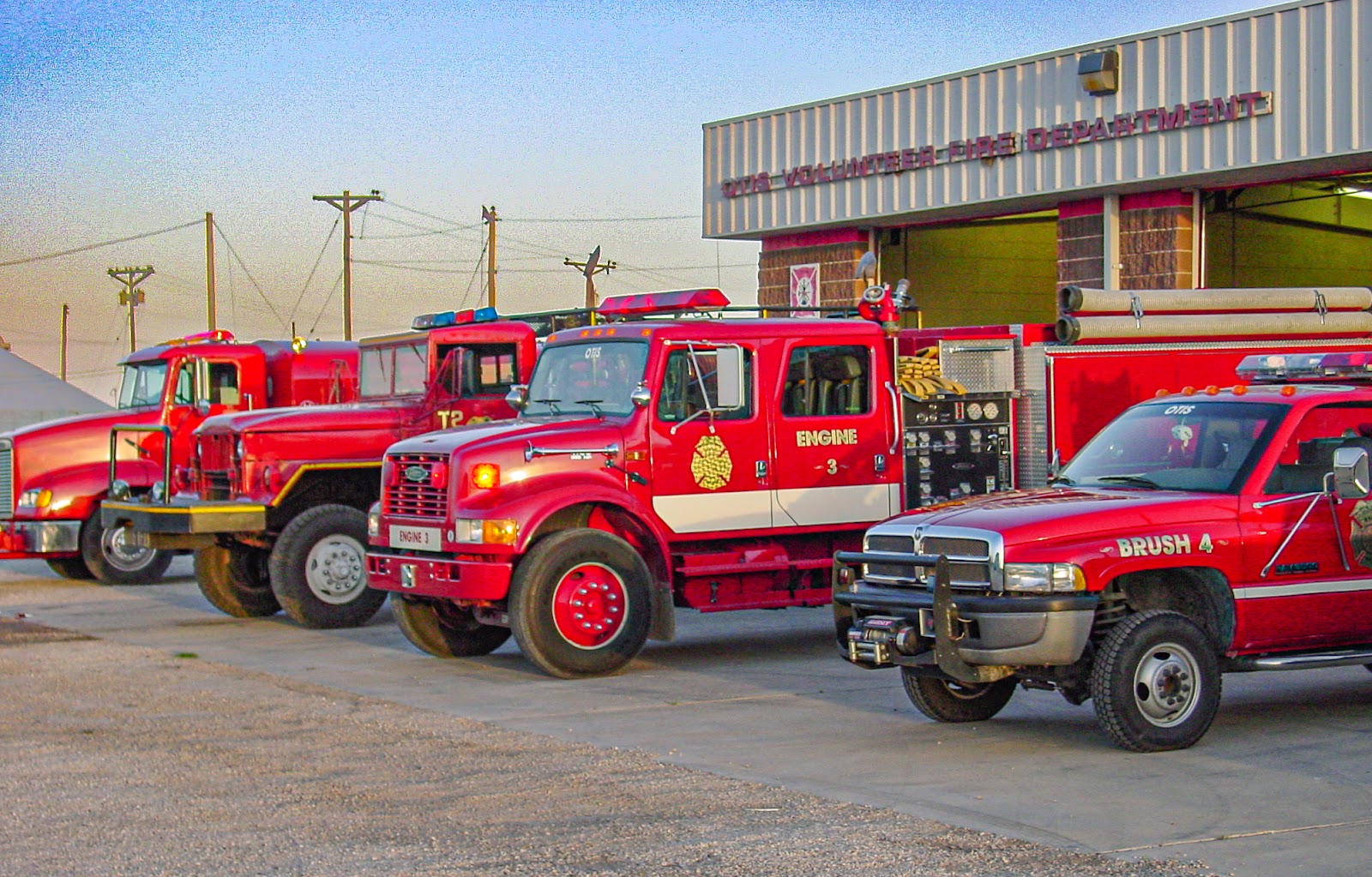 Four red fire trucks parked outside a garage. 